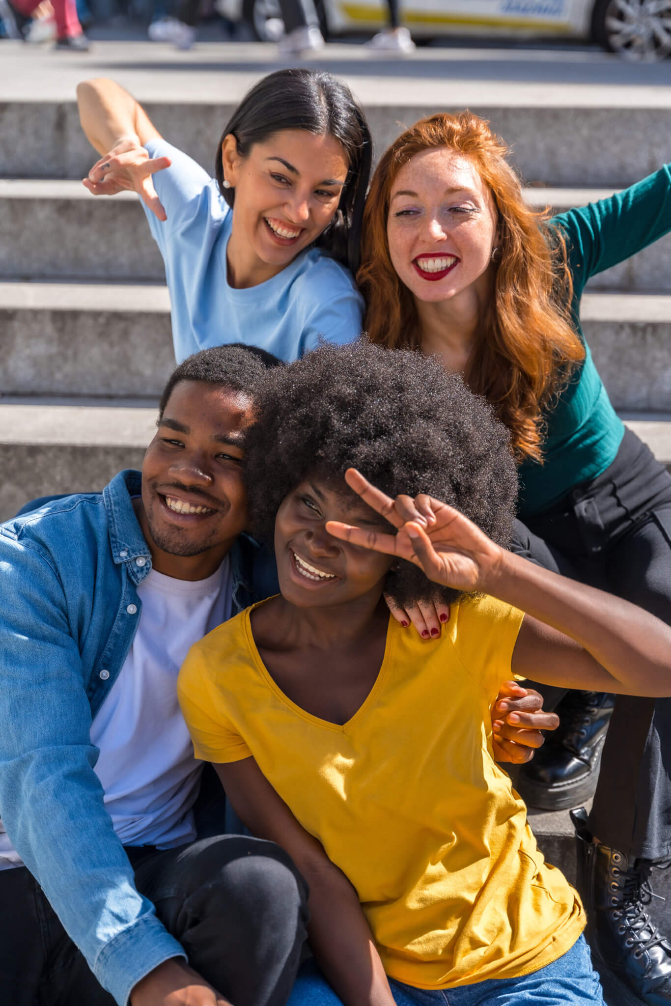 Happy multiethnic friends sitting on stairs in the city having fun, young models